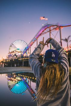 a person standing in front of a ferris wheel with their hand up to the sky