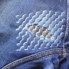 an embroidered patch on the back of a pair of blue jeans with white stitchs