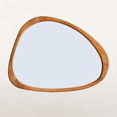 an oval wooden mirror on a white wall