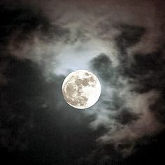 the full moon is seen through some clouds