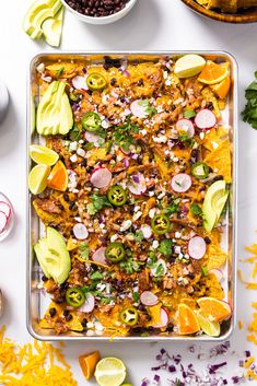 a casserole dish with meat, onions, peppers, avocado and cilantro