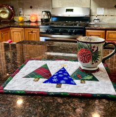 a mug on a kitchen counter with a christmas tree quilted placemat in the middle