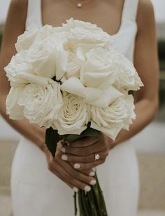 a woman holding a bouquet of white flowers