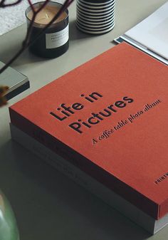 a red book sitting on top of a table next to a vase and other items