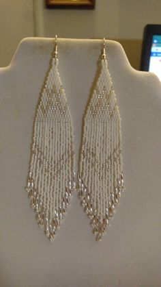 a pair of white beaded earrings sitting on top of a mannequin