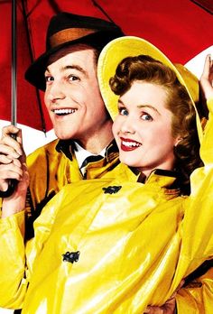 a man and woman in yellow raincoats holding an umbrella