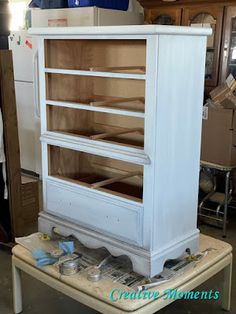 an old white cabinet is being worked on in a shop with other items around it