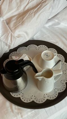 a tray with two cups and saucers sitting on top of a white sheet covered bed