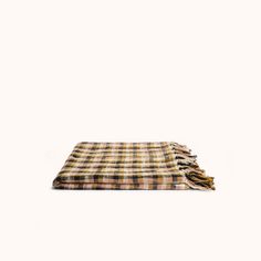 a brown and black plaid blanket laying on top of a white wall