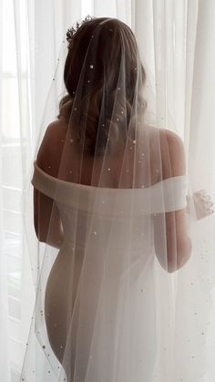 a naked woman wearing a veil in front of a window