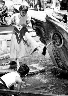 two children are playing in the water near an old boat that has been turned into a fountain