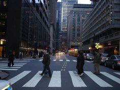 people crossing the street in front of tall buildings