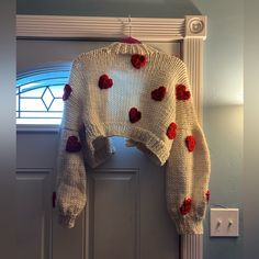 a white sweater with red hearts hanging from the front door