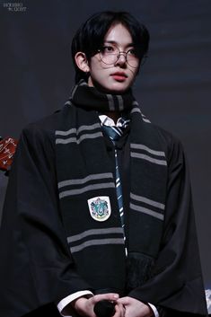 a young man wearing glasses and a harry potter robe is holding his hands in his pockets