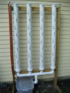 the pipes are attached to the side of the house, and there is a plastic container underneath them