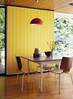 a dining room with yellow wallpaper and chairs