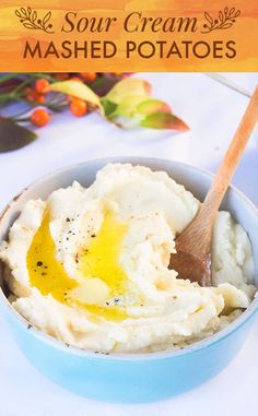 mashed potatoes in a blue bowl with a wooden spoon and text overlay that reads sour cream mashed potatoes