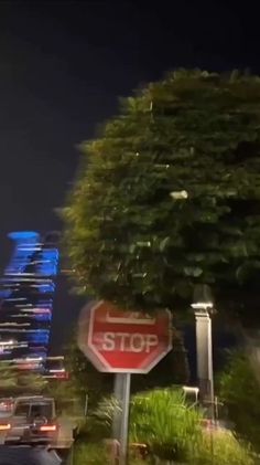 a red stop sign sitting on the side of a road next to a tall building