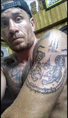 a man with a dragon tattoo on his arm and chest is looking at the camera