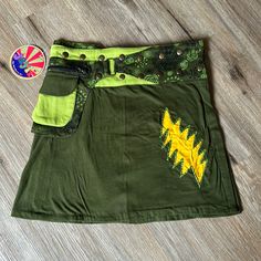 This Is A Perfect Music Festival Skirt! So Cute With Totally Adjustable Waist Band. Can Adjust The Size By Snapping At A Different Length. One Snap Is Coming Off But Could Be Reattached. Pretty Olive Green Color With Cool Design Around Waistband. Has A Zipper Pouch On The Hip As Well As A Velcro Pouch. Yellow Grateful Dead Lightning Bolt On Front! Silk Wrap Skirt, Boho Tie Dye, Perfect Music, Hippie Skirts, Festival Skirts, Hippie Festival, Wrap Around Skirt, Olive Green Color, Silk Wrap