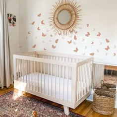 a white crib in front of a wall with butterflies on it and a mirror above the crib