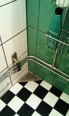 a black and white checkered floor in a bathroom with green tiles on the walls