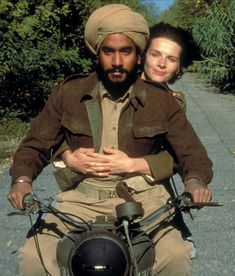 a man riding on the back of a motorcycle next to a woman wearing a turban