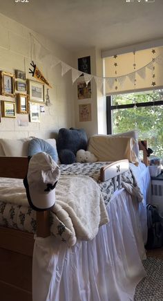 a bed room with a neatly made bed next to a window and pictures on the wall