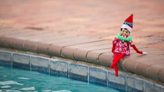 an elf doll sitting on the edge of a swimming pool