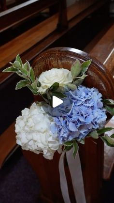 a bouquet of blue and white flowers sitting on top of a wooden bench next to a pew