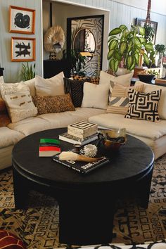 a living room filled with lots of furniture next to a large potted plant on top of a coffee table