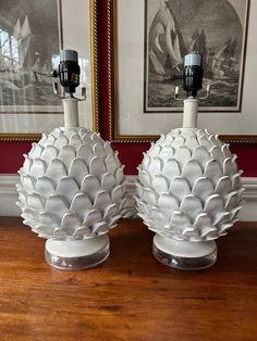 two white vases sitting on top of a wooden table