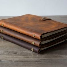 three brown leather notebooks stacked on top of each other