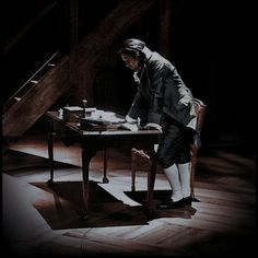 a man standing over a table in front of a stair case