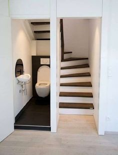 there is a toilet and sink in this bathroom with stairs leading up to the second floor