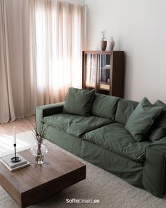 a living room with a green couch and coffee table in front of a large window