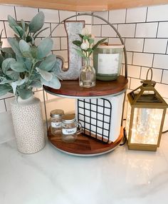 a shelf with candles, jars and flowers on it in a bathroom area next to a candle holder