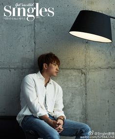 a man sitting under a black lamp next to a cement wall with the words singles written on it