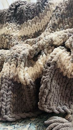 a blanket that is laying on top of a bed with the covers pulled down and crocheted