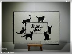 a card with cats on it and the words thank you written in black ink, sitting on top of a wooden easer