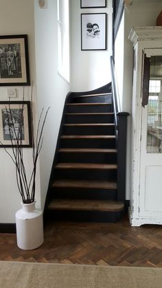 there is a black and white stair case in the house with pictures on the wall