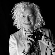 a black and white photo of a woman holding a camera