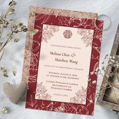 a red and white wedding card next to some flowers