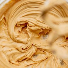 a mixing bowl filled with peanut butter in it's center and being stirred by a whisk