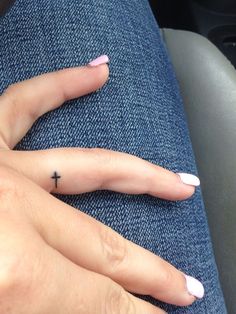 two fingers with small tattoos on them, one has a cross tattooed on the middle finger