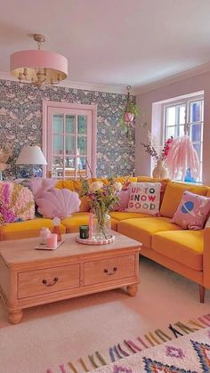 a living room filled with yellow couches and pink pillows on top of a rug