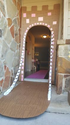 an entrance to a house with pink and white decorations on the front door, next to a purple rug