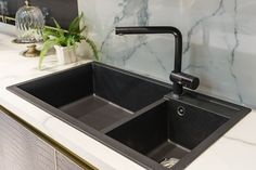 a black sink sitting under a faucet next to a white marble counter top