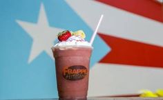 a chocolate milkshake with whipped cream and strawberries on top sits in front of an american flag