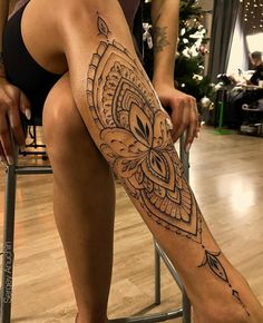 a woman sitting on top of a chair with a tattoo on her leg